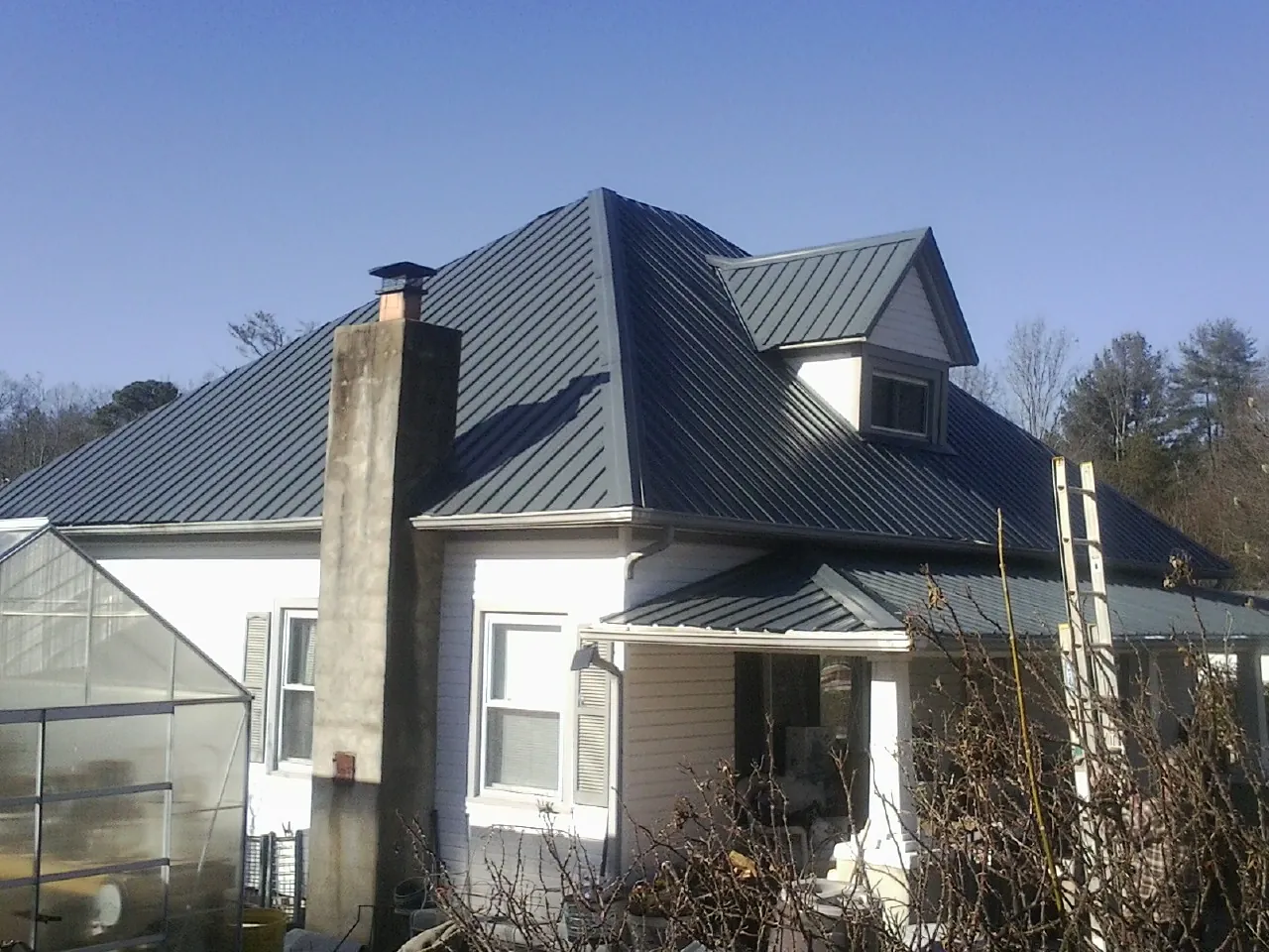 Dark blue standing seam metal roof on a white farmhouse with dormer — Slate & Tile Roof Repair by Roofing Brothers in George