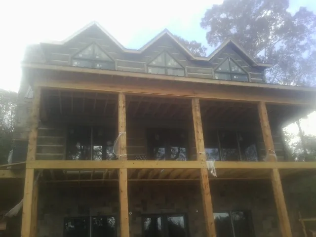 Dormers and porch framing on a large log home under construction — Roof Coating work by our crew in George